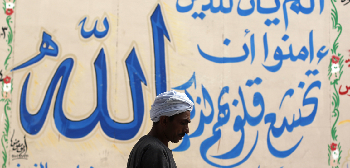 A man walks past a graffiti of verses from the Koran at downtown in Cairo August 21, 2014. The verse reads, "Has not the time arrived for the believers that their hearts in all humility, should engage in the remembrance of Allah". REUTERS/Amr Abdallah Dalsh