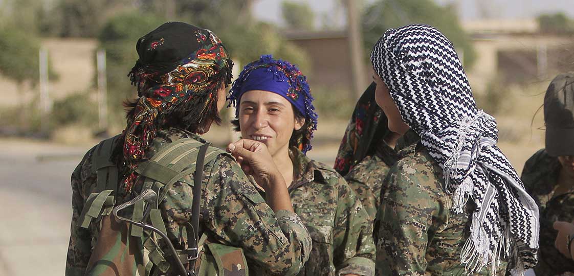 Female fighters of the Kurdish People's Protection Units (YPG) carry their weapons as they talk along a road in Qamishli countryside September 19, 2014. Picture taken September 19, 2014. REUTERS/Rodi Said