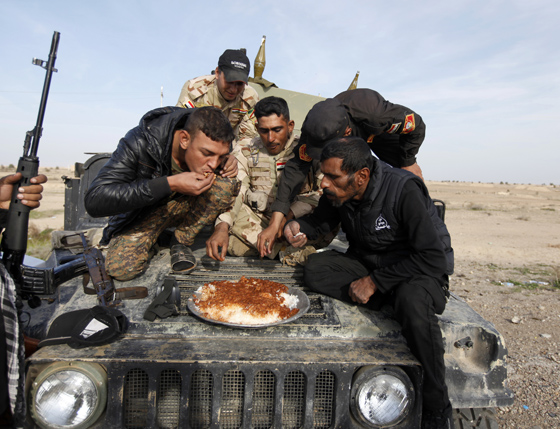 Members of Iraqi security forces and Shiite fighters eat on their vehicle on the outskirts of Baiji, north of Baghdad December 8, 2014. REUTERS/Ahmed Saad 