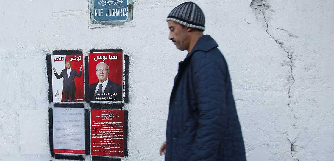 A man walks past election posters of presidential candidates in Tunis December 16, 2014. Tunisia will hold the run-off of its first democratic presidential election on December 21, between incumbent Moncef Marzouki and Beji Caid Essebsi, veteran leader of secularist party Nidaa Tounes, electoral authorities said last week. REUTERS/Zoubeir Souissi