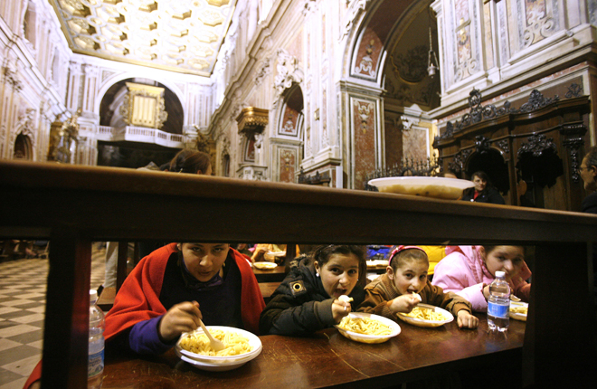 Naples, Italy Girls eat from plates of pasta on a church pew, during the occupation of the Basilica del Carmine in Naples April 22, 2008. The basilica has been the temporary shelter to 348 people, belonging to 130 families who arrived on April 4 after they were evicted from illegally built apartment buildings. REUTERS/Dario Pignatelli