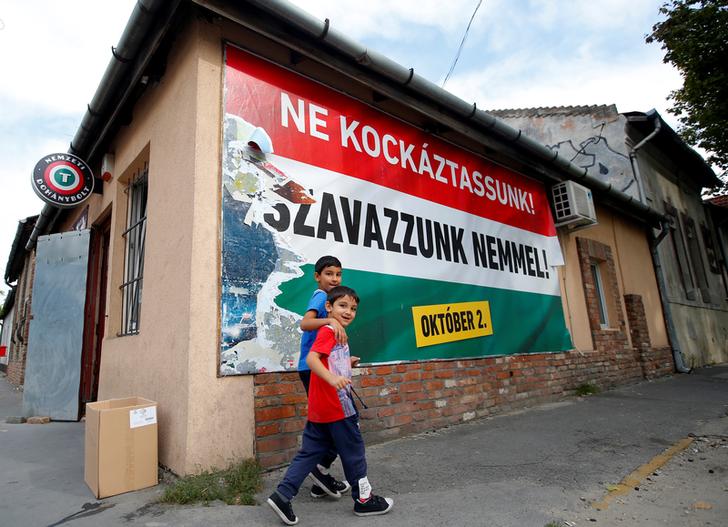 Due ragazzi rom camminano di fronte al poster del Governo ungherese in materia di referendum sulle quote migranti dell'UE a Budapest, 28 Settembre 2016. REUTERS/Laszlo Balogh
