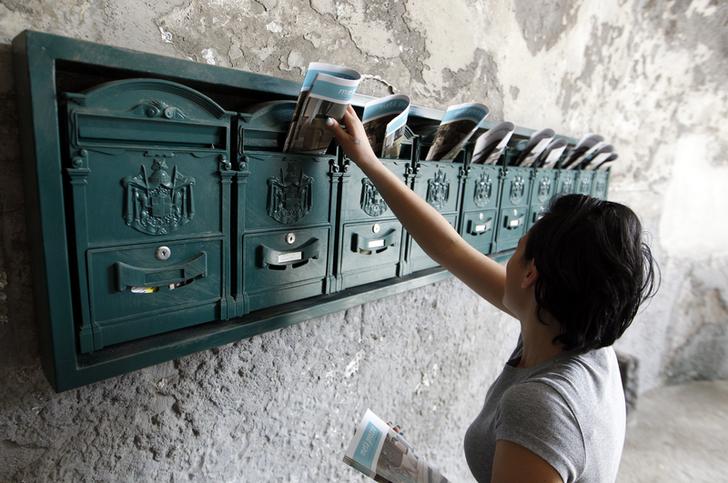Una donna inserisce volantini pubblicitari nelle cassette della posta a Napoli. REUTERS/Ciro De Luca