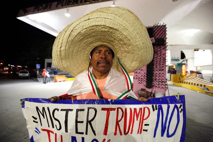Martin Macias holds a placard against U.S. Republican presidential nominee Donald Trump while standing at Paso del Norte international border crossing bridge in Ciudad Juarez, Mexico, November 8, 2016. REUTERS/Jose Luis Gonzalez