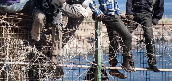 Migranti africani in cima a una recinzione di confine coperta di filo e rasoi (concertinas) tra Marocco e l'enclave spagnola di Melilla. REUTERS / Jesus Blasco de Avellaneda