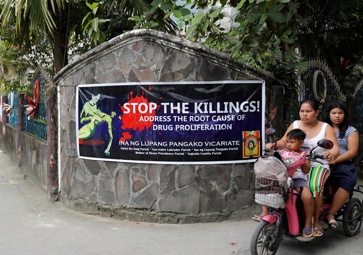 Persone in motorino passano vicino a uno striscione contro le uccisioni legate alla guerra alla droga lungo una strada a Barangay Bagong Silangan, Quezon City, Metro Manila, Filippine. REUTERS / Erik De Castro