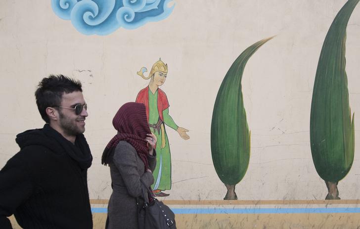 Due giovani camminano vicino a un murales tradizionale iraniano a Tehran. REUTERS/Morteza Nikoubaz