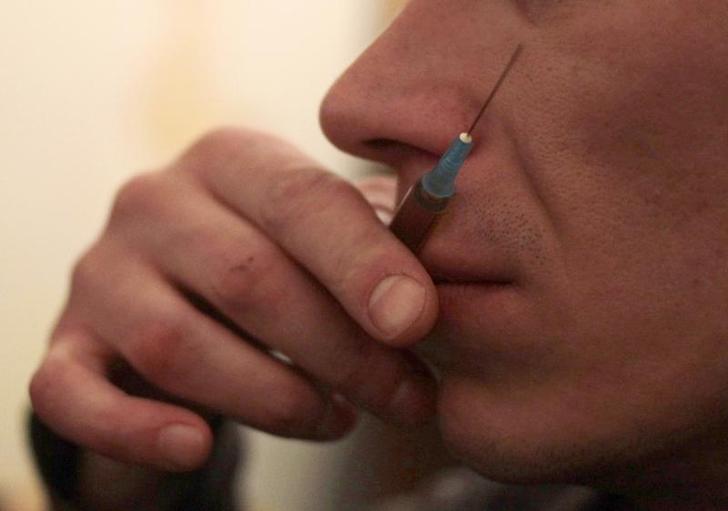 Un tossicodipendente controlla con le labbra la temperatura della siringa di eroina in un appartamento nella città russa di Tver. REUTERS/Diana Markosian