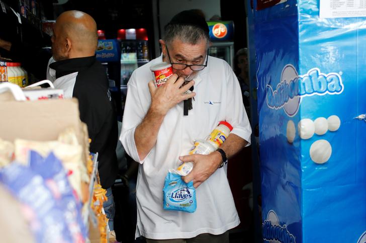 Gente che compra cibo in un minimarket a Caracas. REUTERS/Marco Bello