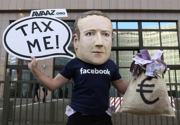 Un’attivista indossa una maschera con il volto del fondatore di Facebook Mark Zuckerberg, durante una manifestazione in occasione dell’incontro tra i ministri delle finanze dell’Unione Europea a Bruxelles. REUTERS/Yves Herman