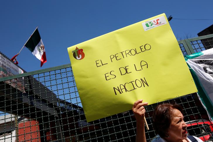Una lavoratrice davanti alla sede centrale di Pemex tiene un cartello con scritto: “Il petrolio è della nazione”. Città del Messico, Messico. REUTERS / Carlos Jasso