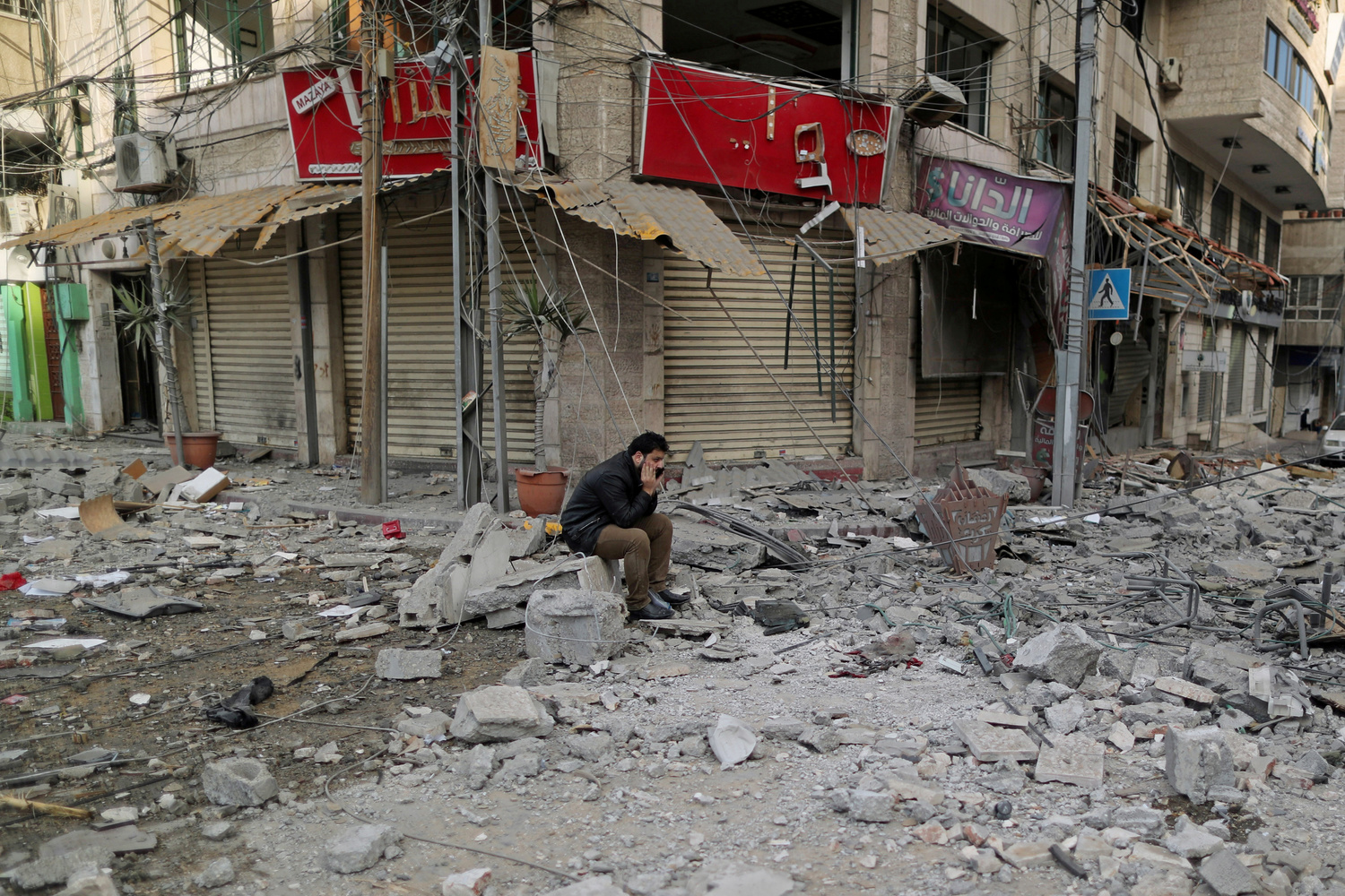 Un uomo palestinese si siede su una maceria fuori da un edificio danneggiato dagli attacchi aerei israeliani, a Gaza, 5 maggio 2019. REUTERS/Suhaib Salem