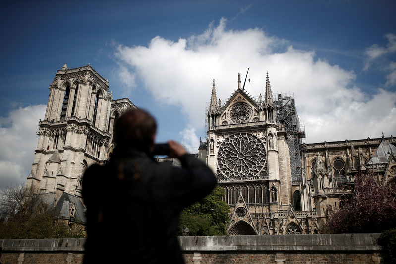 Un uomo fotografa la cattedrale di Notre Dame due giorni dopo l'incendio che ha devastato gran parte della struttura, Parigi, Francia, 17 aprile 2019. REUTERS/Benoit Tessier