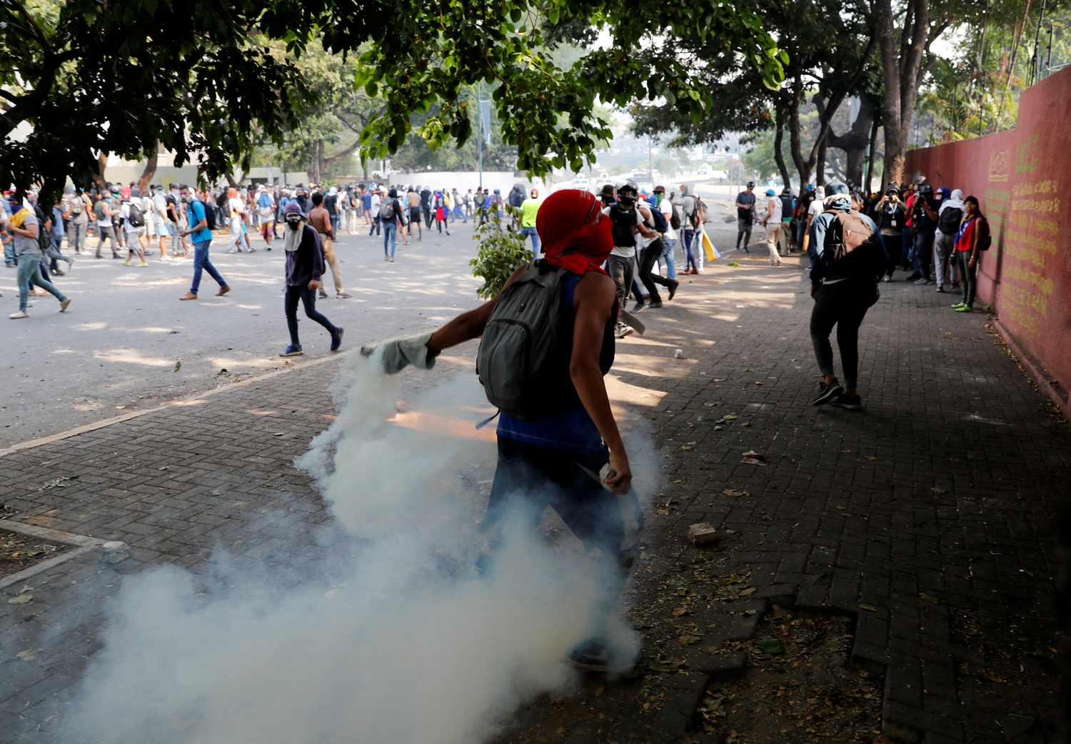 Un dimostrante getta una bomboletta di gas lacrimogeno durante gli scontri con le forze di sicurezza in seguito a una manifestazione contro il Governo del Presidente venezuelano Nicolas Maduro e per commemorare il Primo Maggio a Caracas, Venezuela, 1 maggio 2019. REUTERS/Carlos Garcia Rawlins