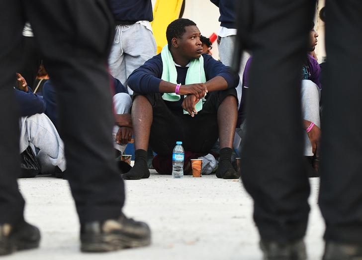 Un migrante si siede a terra dopo essere sbarcato dalla nave di soccorso Sea Watch 3 a Lampedusa, Italia, 29 giugno 2019. REUTERS/Guglielmo Mangiapane