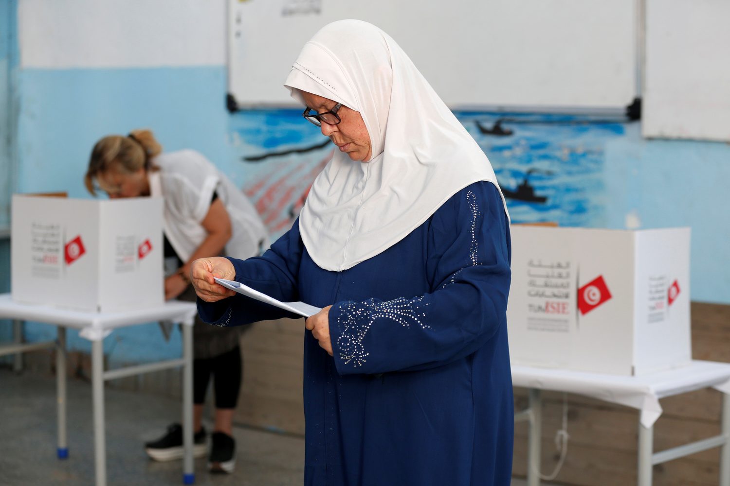 Una donna legge la sua scheda elettorale in un seggio elettorale durante le elezioni parlamentari, a Tunisi, Tunisia, 6 ottobre 2019. REUTERS/Zoubeir Souissi