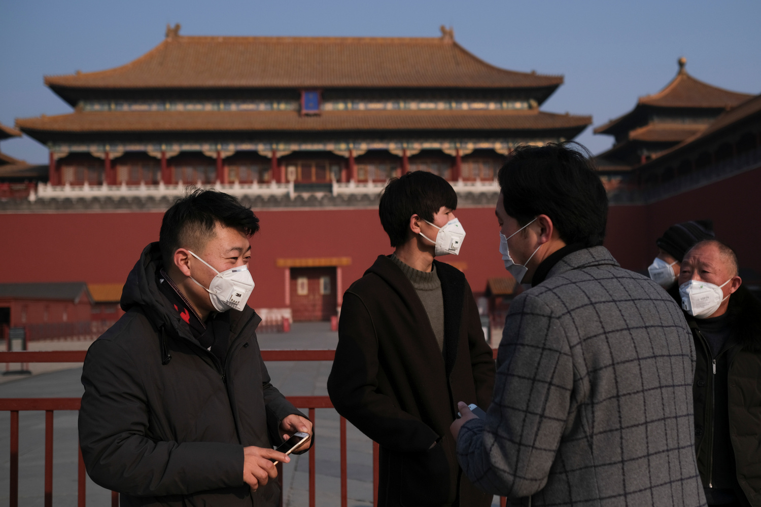 Le persone indossano maschere protettive fuori dall'entrata principale della Città Proibita, a Pechino, Cina, 25 gennaio 2020. REUTERS/Carlos Garcia Rawlins