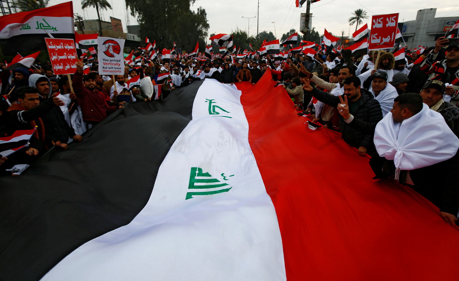 I sostenitori di Moqtada al-Sadr portano un'enorme bandiera irachena in segno di protesta contro la presenza e le presunte violazioni degli Stati Uniti in Iraq, a Baghdad, Iraq, 24 gennaio 2020. REUTERS/Alaa al-Marjani