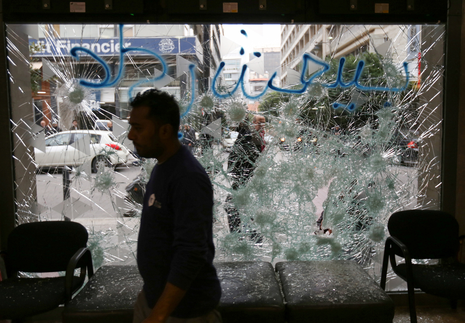 Un uomo si trova vicino a una facciata rotta di una banca a Beirut, Libano, 15 gennaio 2020. REUTERS/Aziz Taher