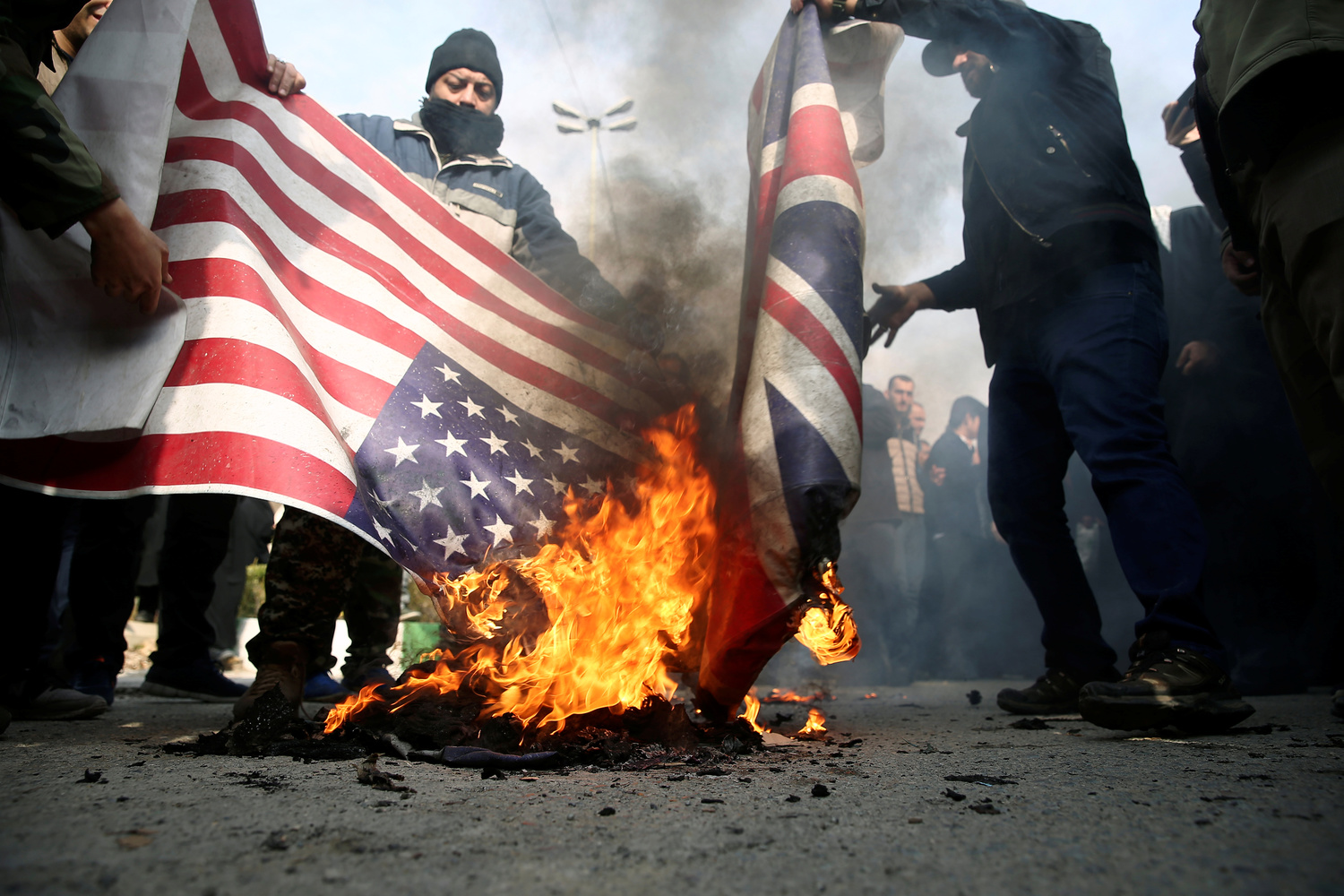 I manifestanti bruciano le bandiere statunitensi e britanniche durante una protesta contro l'assassinio del generale iraniano Qassem Soleimani, capo delle Quds Force, e del comandante della milizia irachena Abu Mahdi al-Muhandis, uccisi in un attacco aereo all'aeroporto di Baghdad, a Teheran, Iran, 3 gennaio 2020. WANA (West Asia News Agency)/Nazanin Tabatabaee tramite REUTERS