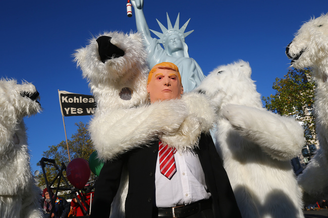 Un manifestante indossa una maschera del Presidente degli Stati Uniti Donald Trump insieme ad altri manifestanti vestiti da orsi polari durante una dimostrazione sotto il cartello 