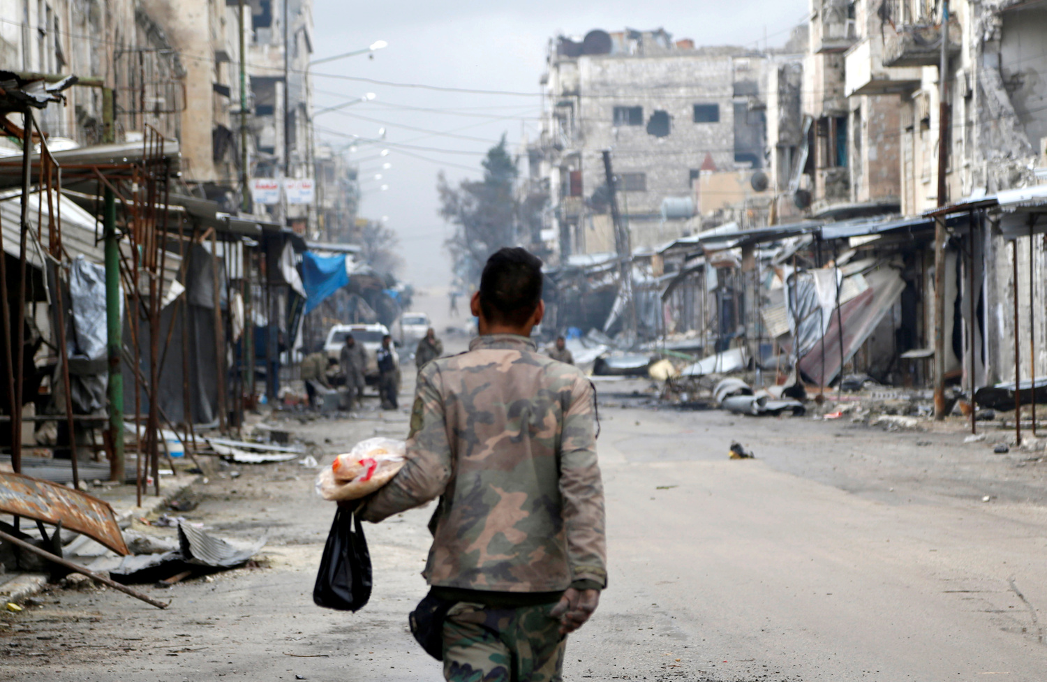 Un soldato dell'esercito siriano trasporta cibo mentre attraversa Maarat al-Numan, Siria, 30 gennaio 2020. REUTERS/Yamam Al Shaar