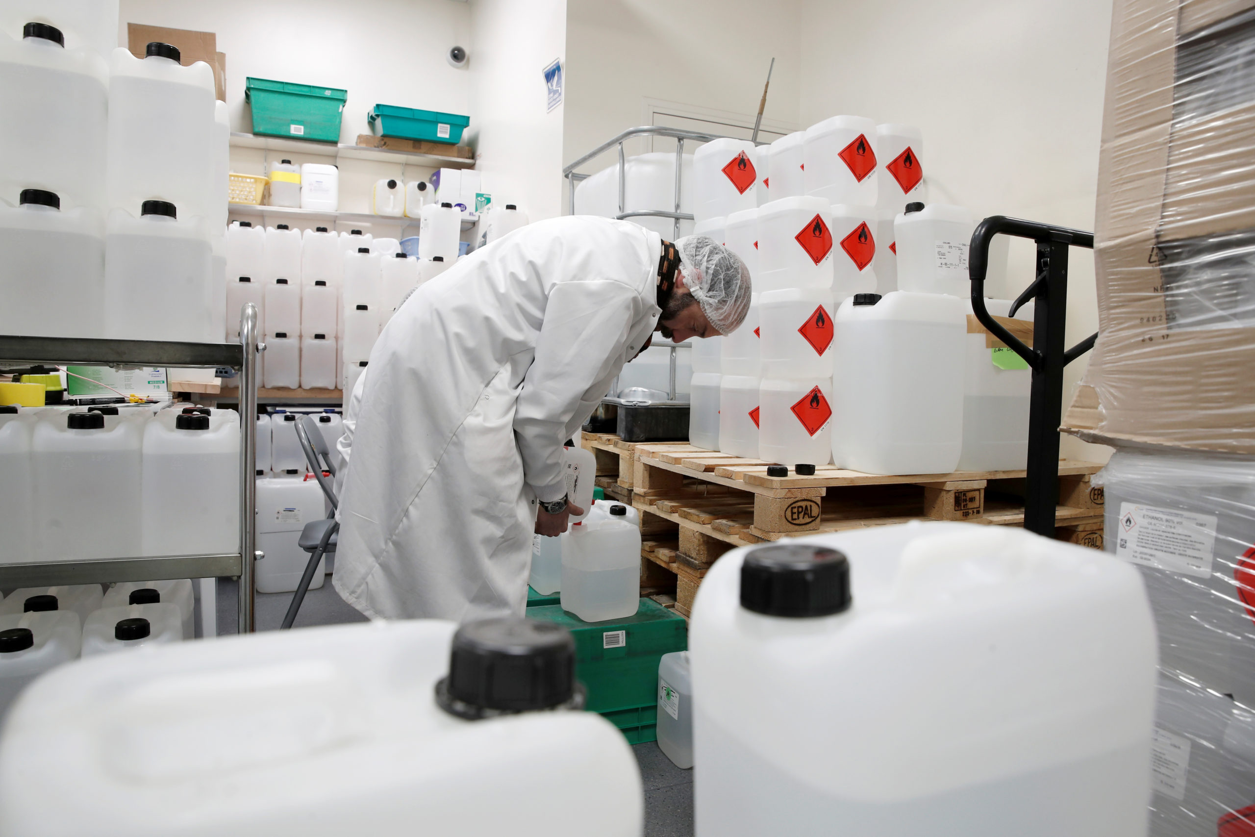 Un dipendente di un laboratorio riempie una tanica di soluzione idroalcolica.